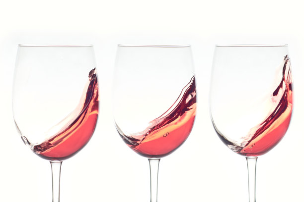 三杯玫瑰葡萄酒洒在白色的背景上。图片下载