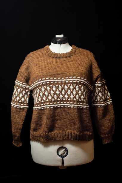 在一个白色的人体模型上手工编织棕色和白色的毛衣。图片下载