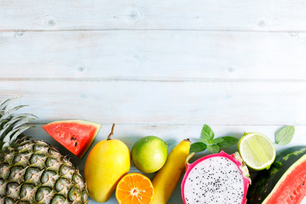夏季水果品种，西瓜菠萝芒果橙龙果，平铺在浅蓝色的木制背景上。图片下载