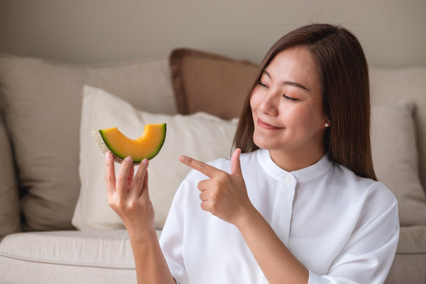 一名年轻女子的肖像，手拿并指着一块哈密瓜图片下载