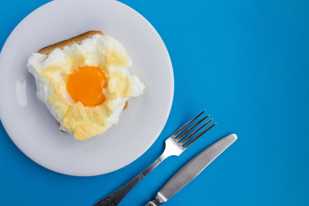 在蓝色背景的白色盘子上夹着鸡蛋的三明治。前视图。副本的空间。图片下载