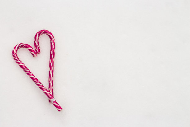 节日简约的白色背景。一颗甜甜的粉色条纹糖果在白雪皑皑的背景上。爱。情人节。情人节的创意礼物。二月十四日。照片与一个地方的题词，俯视图图片下载