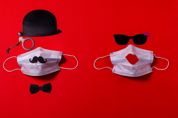 友谊病毒防护。带眼镜的医用口罩，由硬纸板制成，背景是红色的纹理纸。图片下载