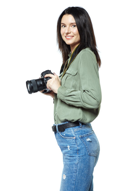 穿着牛仔裤和卡其布衬衫的女摄影师记者拿着相机摆姿势。孤立在白色的。图片下载