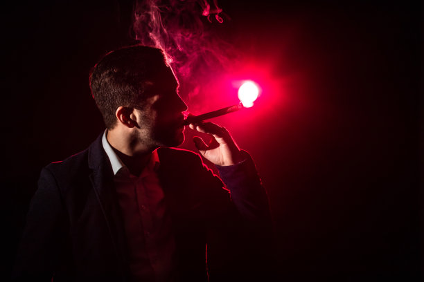 男子在粉红色背景下吸烟的照片。图片下载