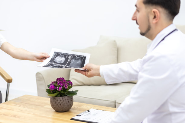 裁切的医生的手照片和超声结果图像在桌面上。图片下载