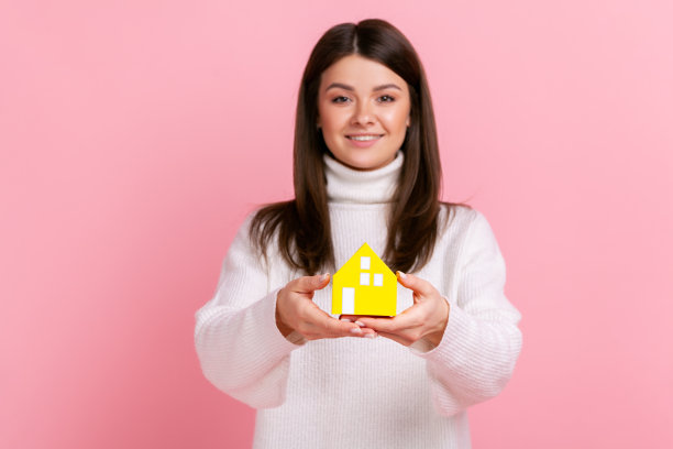 黑头发的美女捧着纸做的小房子，计划买新房，买房。图片下载