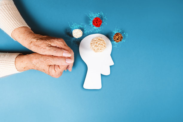 世界阿尔茨海默氏症的一天。一位女性合拢的双手，旁边是一个头部的剪影。编织的球象征着大脑和思想。副本的空间。蓝色背景。心理学的概念图片下载