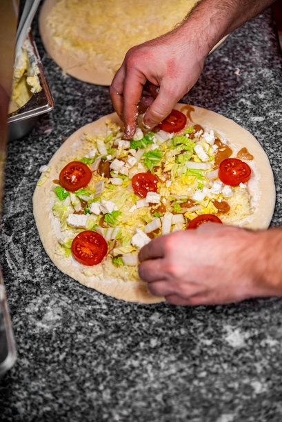 面包师在厨房做披萨的手。制作披萨的过程。烹饪意大利披萨图片下载