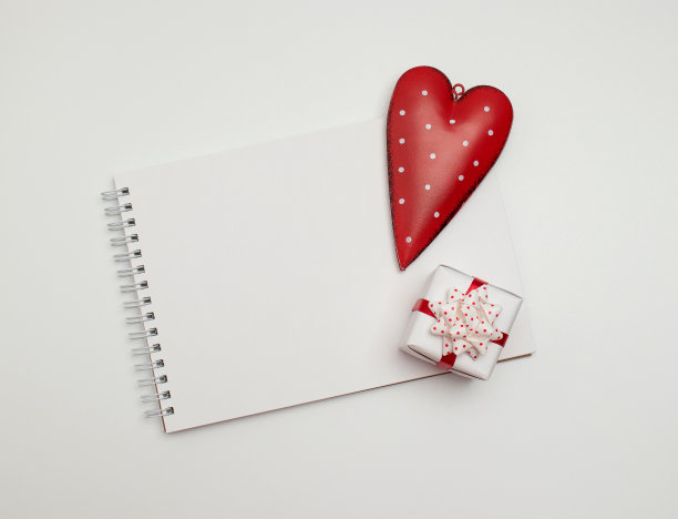 空白的笔记本，一个礼品盒和白色背景上的一颗心。复制空间，俯视图。概念-惊喜和礼物图片下载