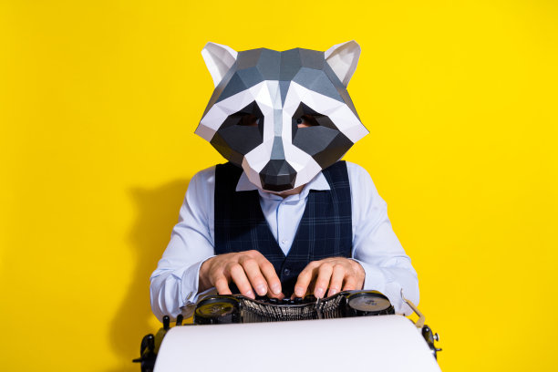 照片疯狂怪诞优雅的家伙记者浣熊面具写新奇的手键写机器孤立在黄色背景图片下载