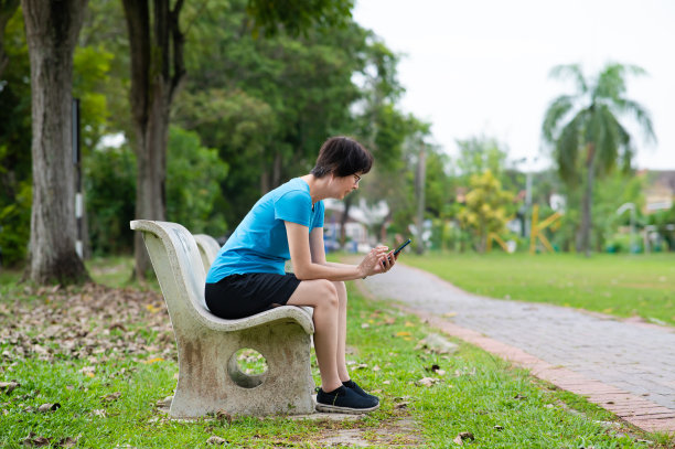 成熟的亚洲女性在锻炼后使用智能手机图片下载