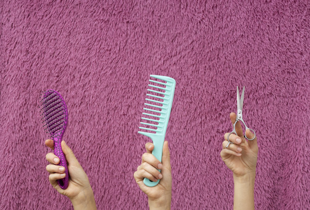 彩色的comsb，刷子和剪刀在妇女的手在粉红色的头发背景图片下载