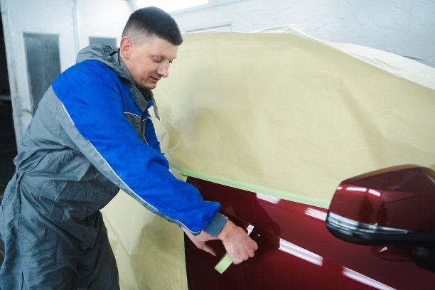 在汽车维修服务中，技师在喷漆前用纸覆盖汽车图片下载