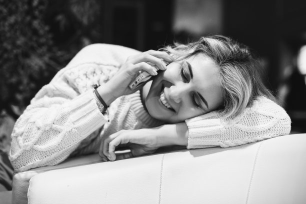 年轻漂亮的女士在餐厅打电话的照片。快乐的微笑。坐在椅子上。头靠在椅子上。图片下载