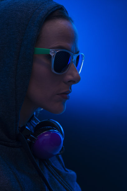 一个穿着连帽衫、太阳镜和耳机的女人的肖像。图片下载