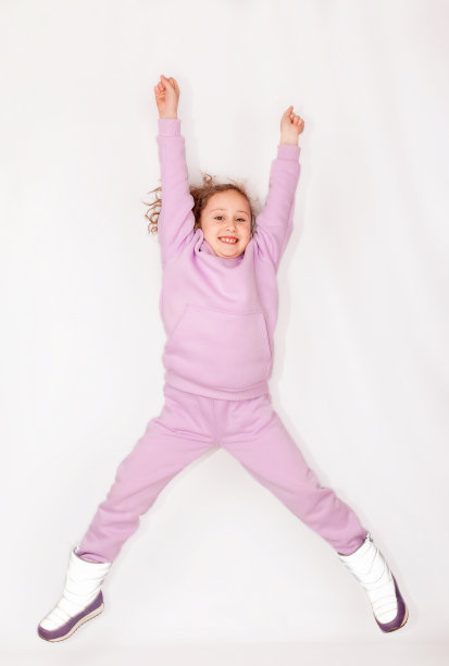 一个可爱的小女孩穿着粉红色的裤子和一件巨大的紫色连帽衫图片下载