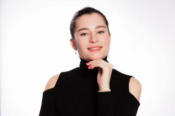 短发，皮肤干净的女人。脸近，皮肤美黑，美丽的微笑的女人在黑色高领在白色的背景图片下载