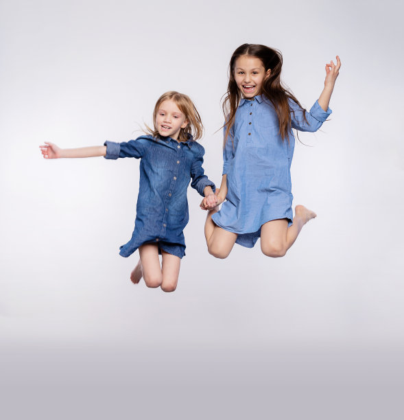 两个兴奋的可爱的孩子女孩喜欢跳开嘴孤立在灰色背景的全尺寸肖像。爱的姐妹或朋友跳起来玩耍，玩得很开心图片下载