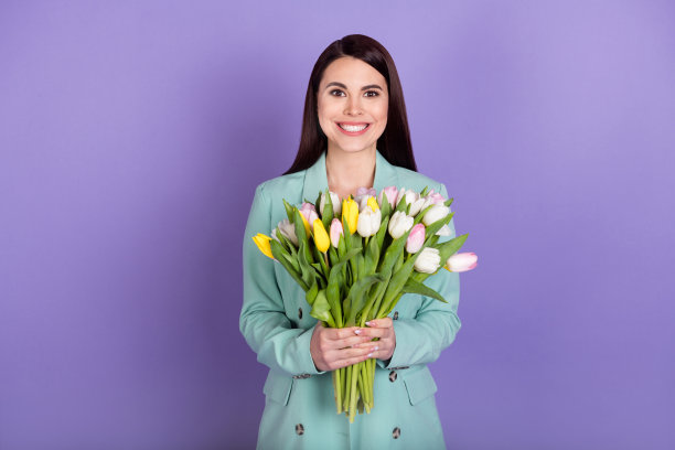 照片正面快乐漂亮的女士抱着郁金香花微笑礼物孤立在紫色的颜色背景图片下载