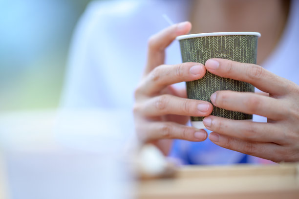 这名女子的手在咖啡店里拿着咖啡杯。图片下载