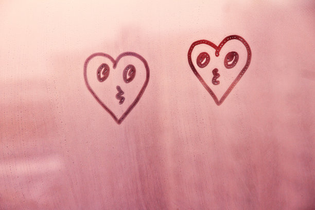 画上亲吻的脸心形在朦胧的玻璃上在夕阳的窗户上图片下载