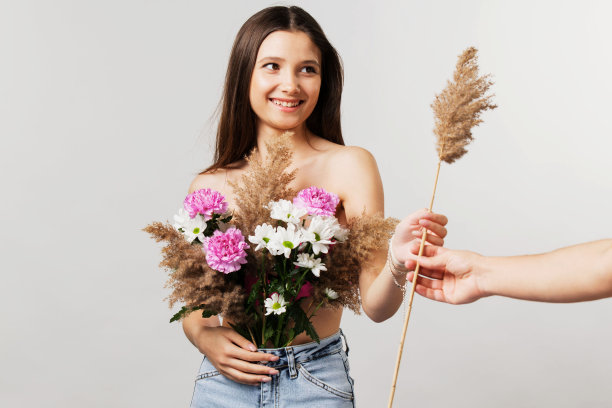 年轻的女士藏着她的乳房，用一束花盖住它，从一个男人手里拿了一份早午餐芦苇看着他。图片下载