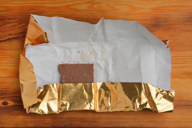 在木质的表面上用箔纸包着的一块巧克力图片下载