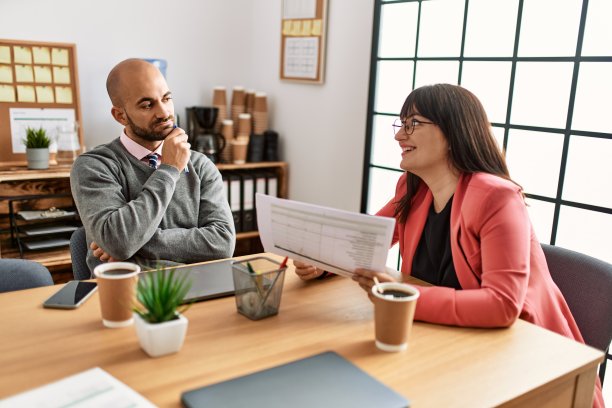 图为，两名西班牙裔企业职员正在办公室里愉快地工作。图片下载