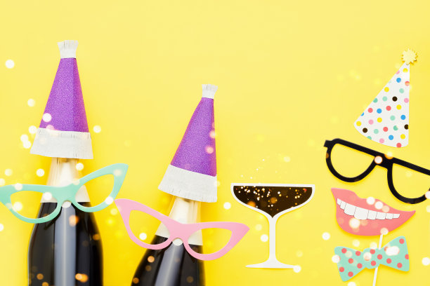 节日背景与派对道具，面具，和香槟在明亮的黄色背景。图片下载