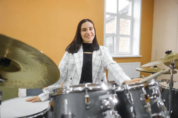 一幅年轻美丽的成年女子的肖像，站在一套鼓后面。爱好和消遣。图片下载