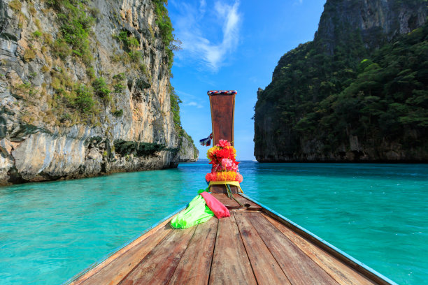 头长尾船在海和悬崖岩石山的背景图片下载