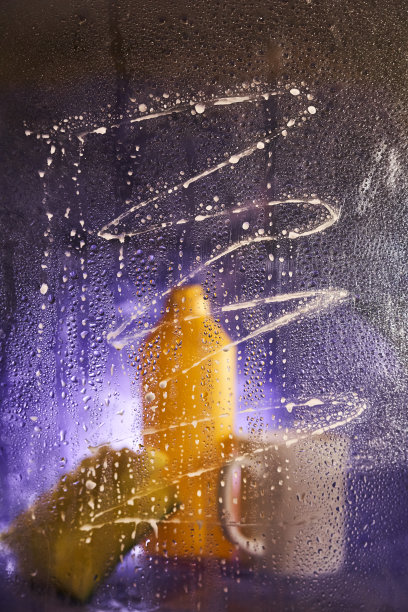 透过脏玻璃看。家庭清洁产品和厨房配件的特写。在深紫丁香色的背景上图片下载