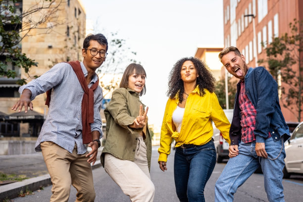 来自不同种族的朋友们在街上嬉闹着走着，他们有着聚会的心情，快乐的大学生们表演着有趣的舞步，微笑的年轻人在城市的街道上翩翩起舞图片下载