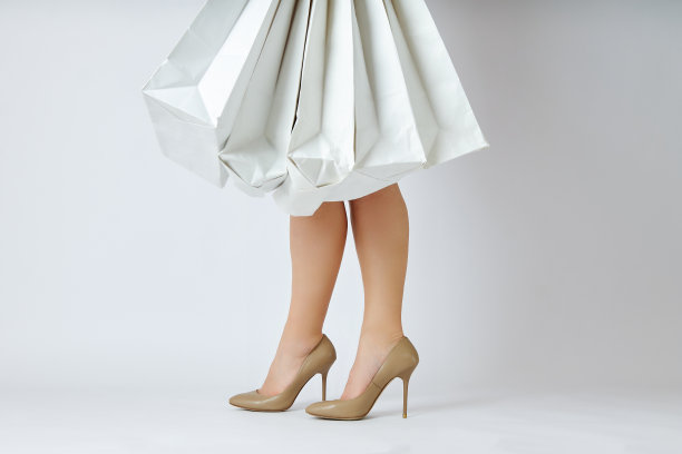 美丽的腿年轻女人购物袋在白色的背景图片下载