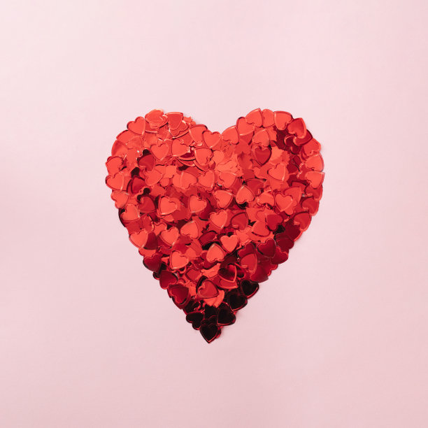 一束创意的五彩纸屑在心形的粉彩背景上。为节日或派对的概念。图片下载