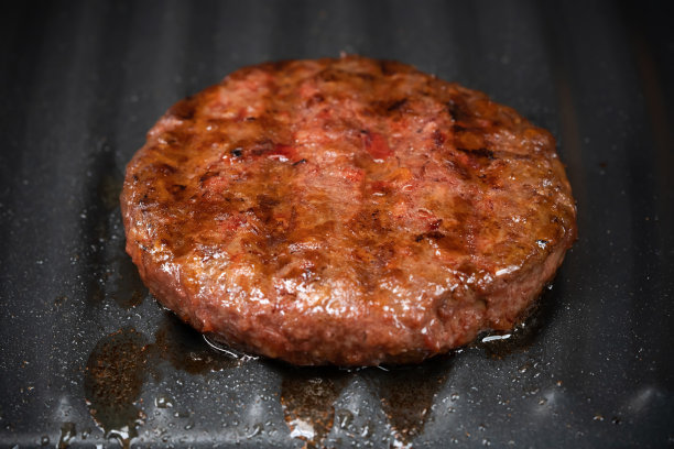 在烧烤盘上烤蔬菜肉的过程。大豆假肉饼，无麸质，非肉类素食和纯素食品的概念。生的汉堡。特写照片。图片下载