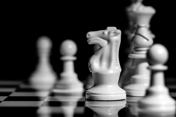 近的国际象棋棋子在一个反射镜板表面与黑色背景图片下载