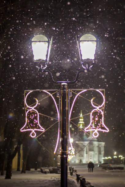 近距离的照片，一盏路灯在黑暗的冬天飘落的雪花。街道装饰为圣诞节和新年。晚上神奇的气氛。晚上的街道。街头复古的照明图片下载