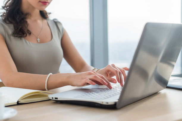 在家里做文案的女人。近距离照片的女性手在电脑键盘在灯光办公室。图片下载