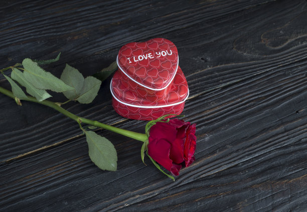 一张木桌上的特写照片，浪漫的红玫瑰和心形糖果盒。图片下载