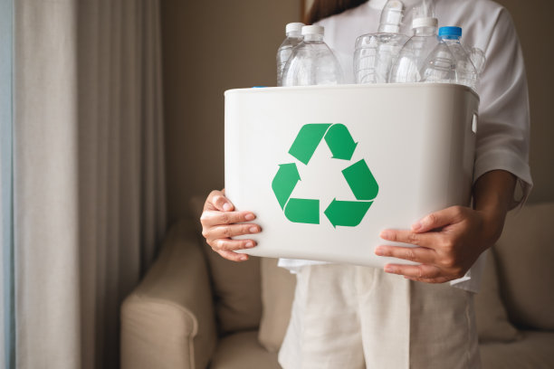 一名妇女在家中收集可回收的塑料瓶并将其分装到垃圾桶中图片下载