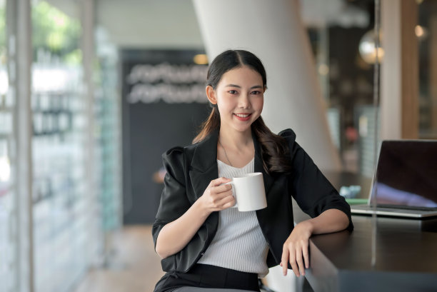 在办公室喝咖啡的年轻亚裔女商人图片下载