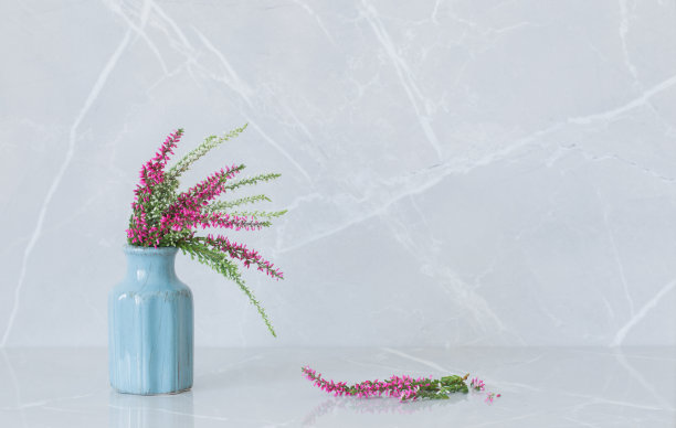 石南花束在灰色大理石背景上的蓝色花瓶图片下载