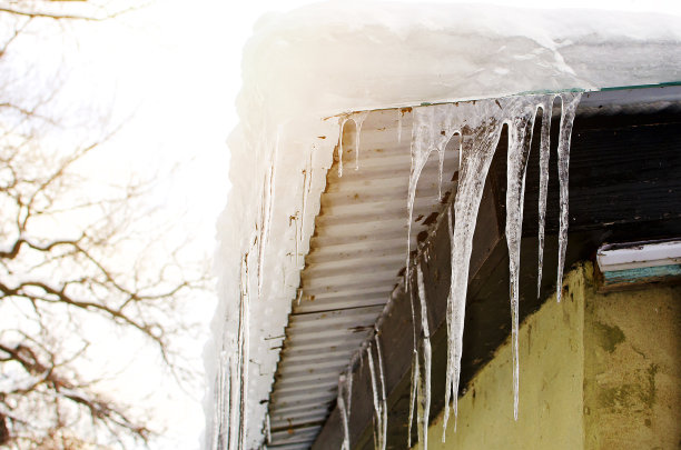 长长的透明的冰柱悬挂在屋顶上，在阳光下闪闪发光。图片下载