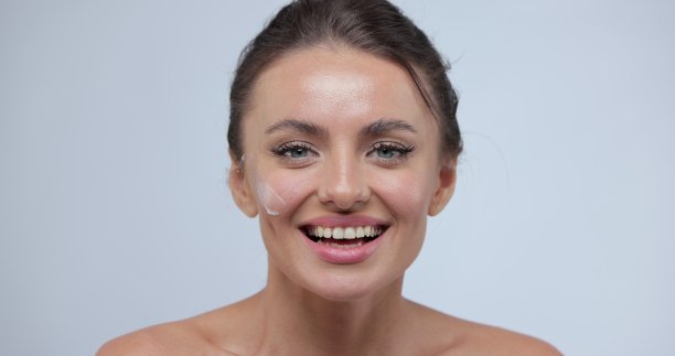 年轻女子的肖像用她的面霜。概念清新保湿肌肤美丽特写美容脸快乐健康的模型。皮肤护理的概念。图片下载