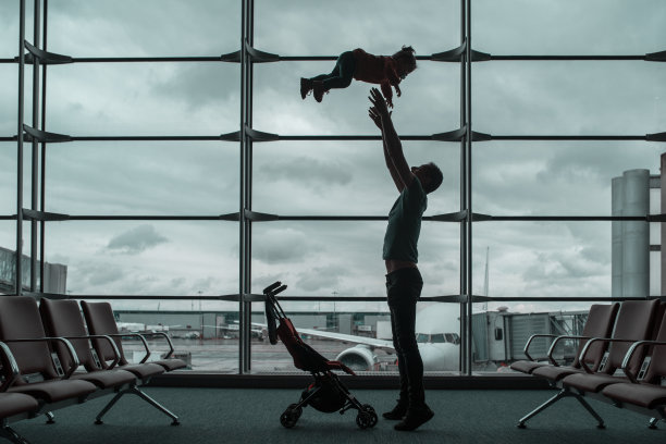 父亲和女儿在机场候机室玩耍，家庭旅行概念图片下载