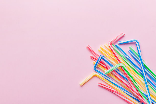 彩色的塑料吸管堆在彩色的背景上，平坦地躺着。文本的复制空间图片下载