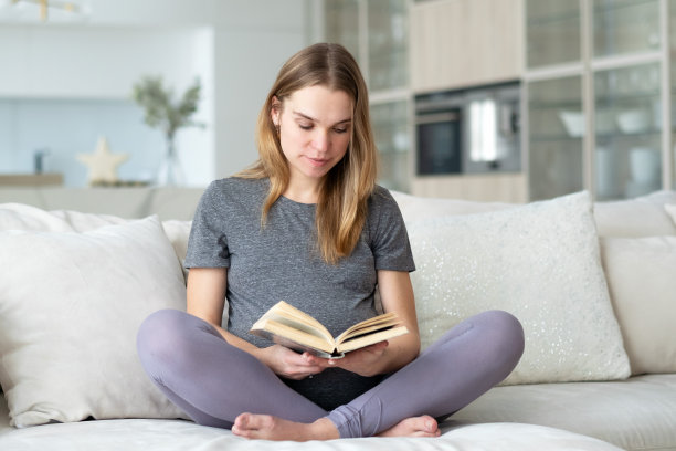 一个孕妇坐在客厅的沙发上看书。图片下载