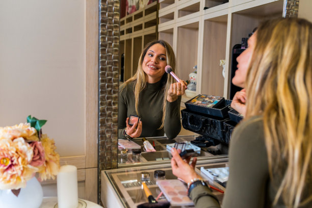 美丽的深色头发的女人在镜子前化妆一个晚上的约会。图片下载